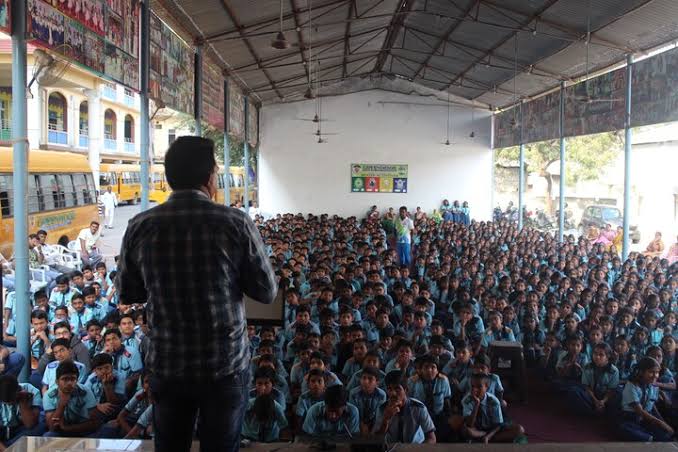 Photo of person speaking to a large audience.