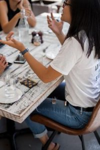 Young woman animatedly talking to friend at table